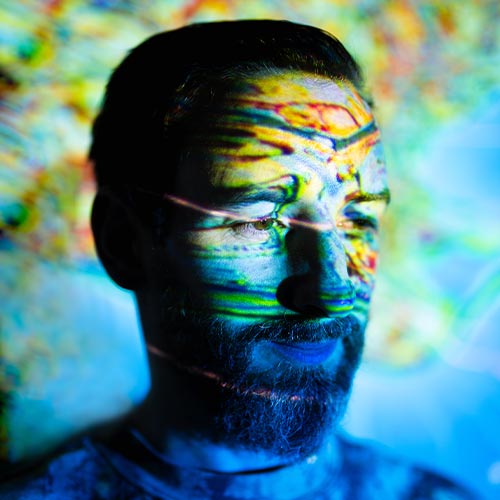 Le producteur électro Max Cooper sous un jeu de lumières psychédéliques, reflétant son univers musical expérimental.