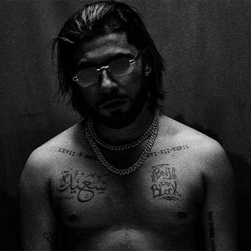 Le rappeur El Grande Toto, dans une esthétique sombre et intense, torse nu avec bijoux et tatouages.